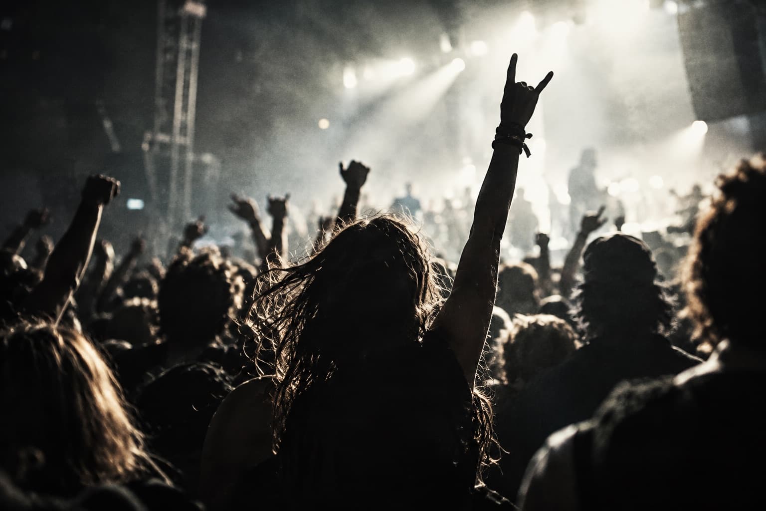 Concert crowd raising their hands toward a lit stage